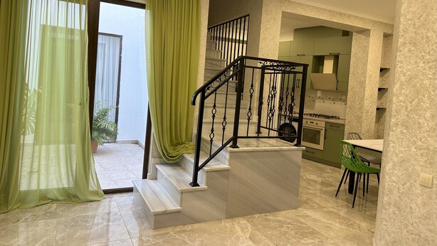 A modern interior with a staircase, a kitchen area, and a dining space.