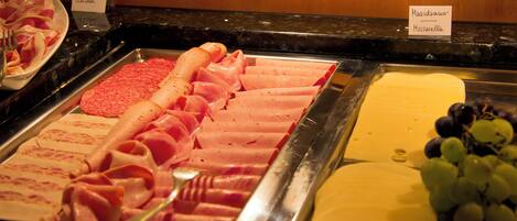A buffet with various meats and cheeses.