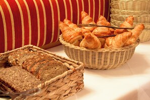 Ein Korb mit Croissants und ein Brotlaib auf einem Tisch.