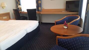 Ein Hotelzimmer mit Bett, Schreibtisch, Fernseher und zwei Stühlen.