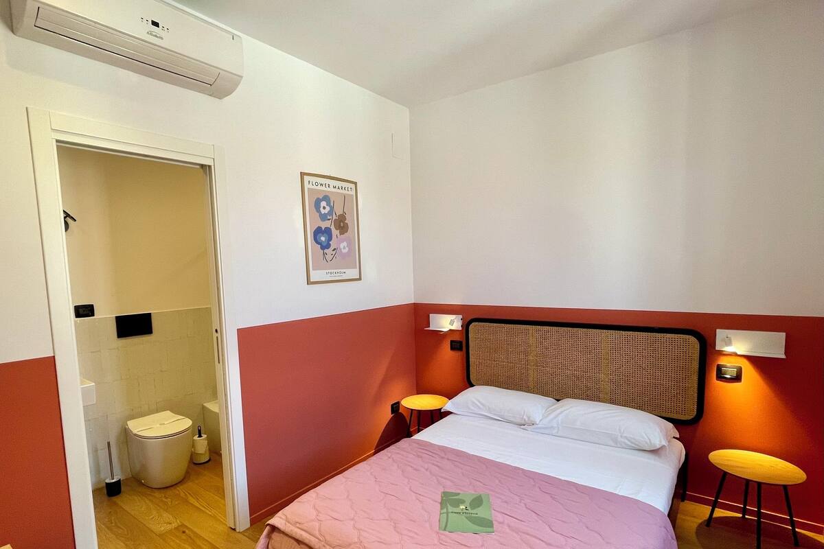 Een hotelkamer met een bed, nachtlampjes, een toilet en een douche.