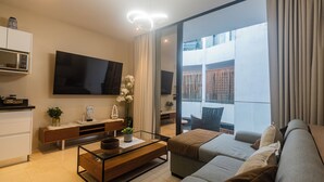 Un salón moderno con televisor de pantalla plana, un sofá, una mesa de centro y un balcón con vistas.