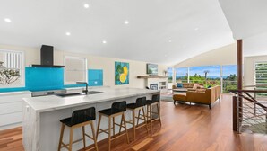 Una cocina moderna con una isla grande, taburetes de bar y un comedor con sofá.