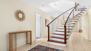 Un interior moderno con una escalera de madera, una consola y un espejo decorativo.