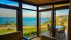 A room with large windows offering a view of the sea and a distant landscape. - Sahil Kamp Istanbul Hotel (Sile)