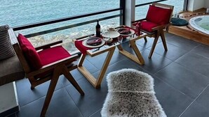 A balcony with a view of the sea, furnished with two red chairs, a small table, and a fluffy rug. - Sahil Kamp Istanbul Hotel (Sile)