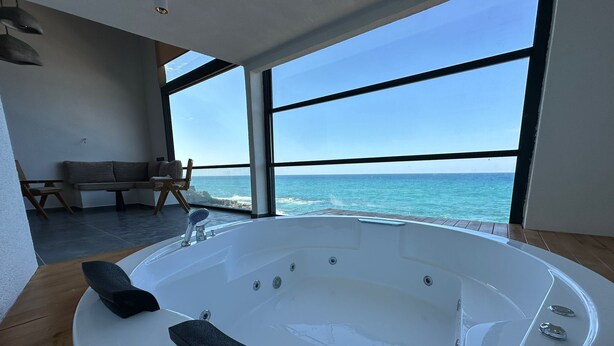 A modern bathroom with a large bathtub, wooden flooring, and a view of the ocean. - Sahil Kamp Istanbul Hotel (Sile)