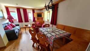 Une pièce chaleureuse avec une table à manger en bois, des chaises, un canapé et un téléviseur posé sur un meuble en bois.