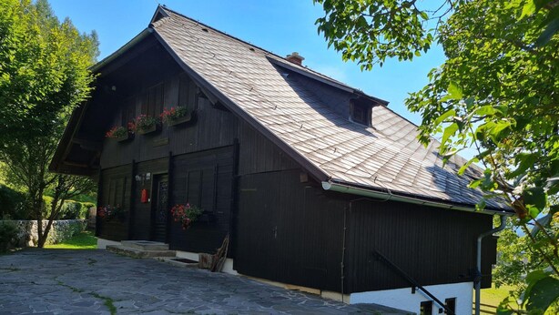 Une maison traditionnelle en bois, dotée d’un toit à pente, d’une entrée pavée de pierres et d’un jardin bien entretenu.