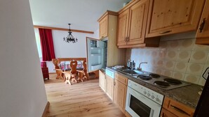 Une cuisine avec des meubles de rangement en bois, une cuisinière et un coin repas comprenant une table et des chaises.