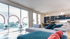 A modern living room with a sofa, a dining area, and a kitchen. - Villa with heated pool 2 steps from the sea (Quartu Sant'Elena)