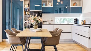 A modern kitchen with a wooden table and two chairs, a vase of flowers, and blue cabinets. - Villa with heated pool 2 steps from the sea (Quartu Sant'Elena)