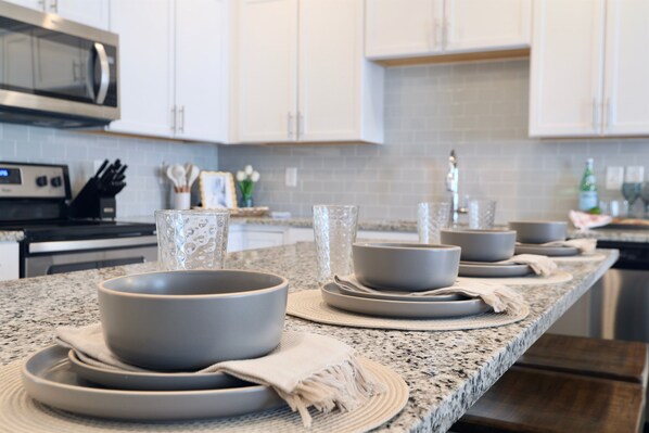 A kitchen with granite countertops, white cabinets, and a stainless steel microwave.