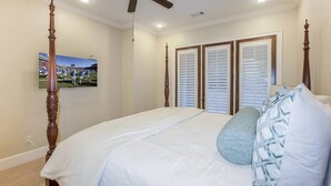 Een slaapkamer met een hemelbed, een plafondventilator en een groot raam met zonwering.