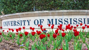 Een bord van de University of Mississippi, voor de bloemen rood tulpen.