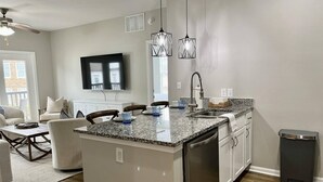 Una cocina moderna con encimera de granito, electrodomésticos de acero inoxidable e iluminación colgante.