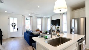 A modern kitchen with a central island, stainless steel appliances, and a ceiling fan.