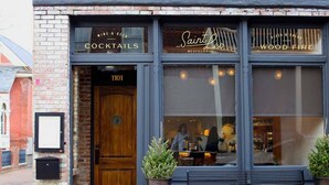 Un restaurante con fachada de ladrillo, una puerta de madera con la inscripción "1101" y un letrero que dice "Saint Leo Restaurant".