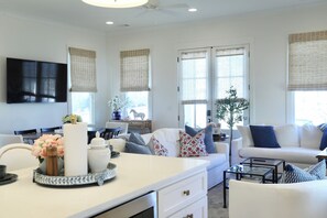 A modern living room with a white sofa, a glass coffee table, and a dining area with a table and chairs. - The Bluebonnet - Stunning Southern Charm Retreat! (Oxford)