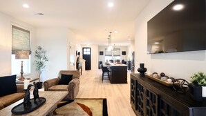 A spacious living area with a sofa, coffee table, and a dining area with a bar.
