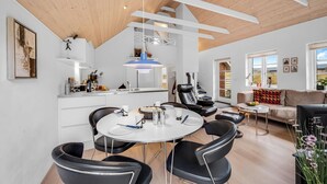 A modern living room with a round dining table, black leather chairs, a sofa, and a TV. - Modernized holiday home, centrally located in one of Søndervig's best locations (Ringkøbing)