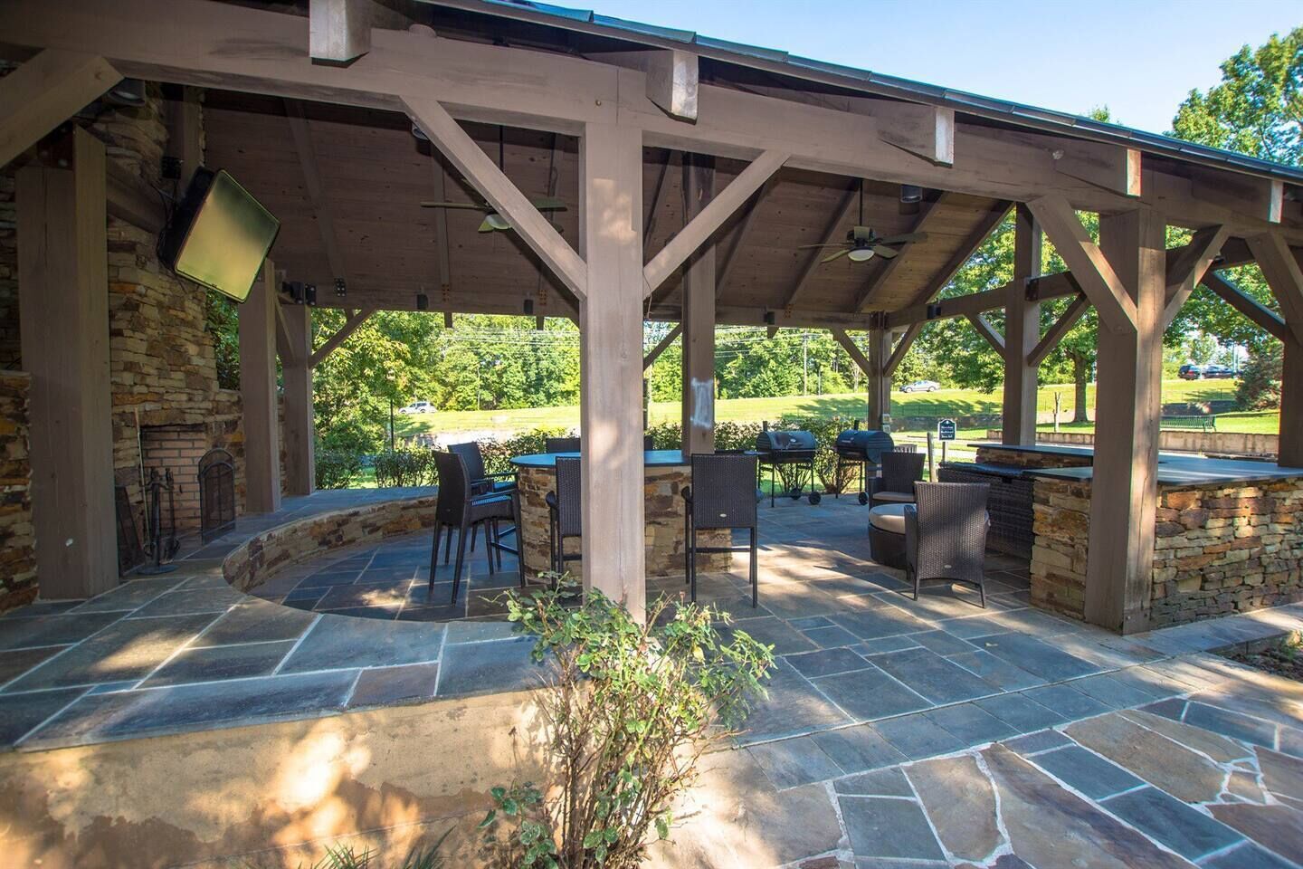 An outdoor patio with stone flooring, wooden pergola, and outdoor seating.
