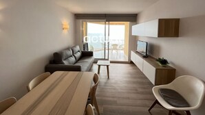 A modern living room with a sofa, a dining table, and a TV.