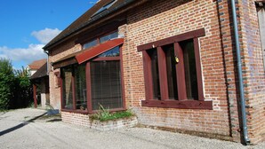 A brick building with large windows and a red awning. - Cottage in Sologne with enclosed garden, pets allowed, parking and internet (Neung-sur-Beuvron)