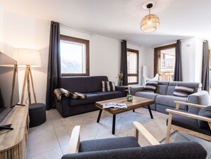 Una sala moderna con sofá, sillones, una mesita de centro y una lámpara de pie.