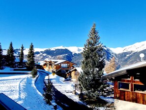 A snow-covered mountain village with wooden buildings, a clear sky, and a ski trail. - New 5-room Apartment 20m from slopes with double garage (La Plagne Montalbert)