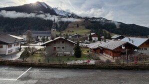 Un village de montagne aux bâtiments traditionnels, avec une église et une vue dégagée sur les sommets enneigés.