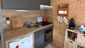 Une cuisine de taille réduite, équipée d’un évier, d’une cuisinière et d’un petit réfrigérateur.