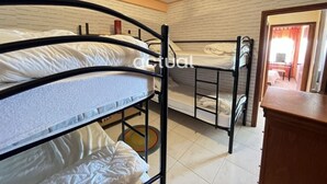 Una camera del dormitorio con letti a castello, una cassettiera in legno e una parete con motivo a mattoni.
