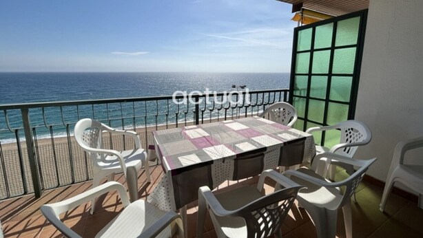 Un balcone con tavolo e sedie, vista mare.