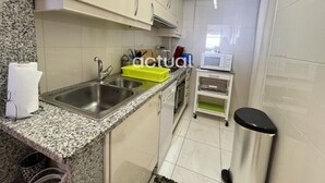 Una cucina con piani di lavoro in granito, lavelli in acciaio inossidabile, un forno a microonde e un piccolo cestino.
