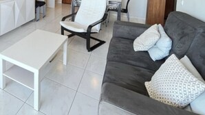 Un soggiorno moderno con un divano grigio, cuscini bianchi e un tavolino da caffè bianco.