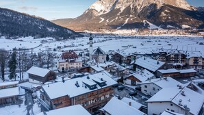 Une ville aux bâtiments couverts de neige, avec une montagne imposante en arrière-plan.