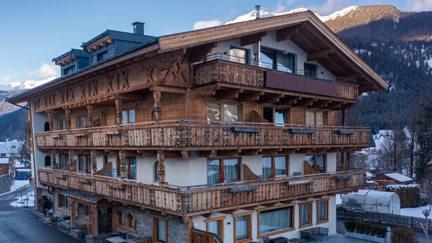 Un chalet en bois à plusieurs étages, doté de balcons, de grandes fenêtres et de fondations en pierre.