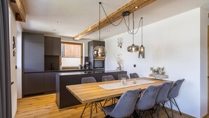 Une cuisine moderne avec des meubles de couleur sombre, un îlot central en bois et des luminaires suspendus.