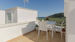 A white balcony with a table and chairs, overlooking a coastal landscape. - Little House in the Junno (Mattinata)