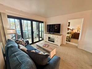 A living room with a sofa, TV, and a glass door leading to an outdoor area. - Waterfront Cabana Unit in Popular Anglers Cove-Check it Out ! (Marco Island)