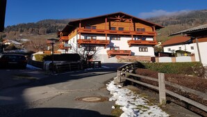 Un immeuble en bois à plusieurs étages, doté de balcons, avec une route pavée devant et de la neige au sol.