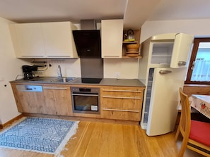 Eine kleine Küche mit Geschirrspüler, Backofen, Spüle und integriertem Kochfeld.