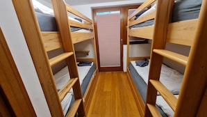 Une chambre avec des lits superposés, des montants en bois et un plancher en bois.