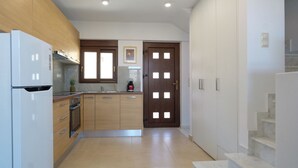 A modern kitchen with wooden cabinets, a white refrigerator, and a coffee maker on the counter. - Villa Ariadni Agia pelagia close to the beach up to7-8 quests (Agia Pelagia)