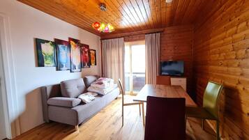 Una habitación con paneles de madera, un sofá, una mesa de comedor y un televisor.