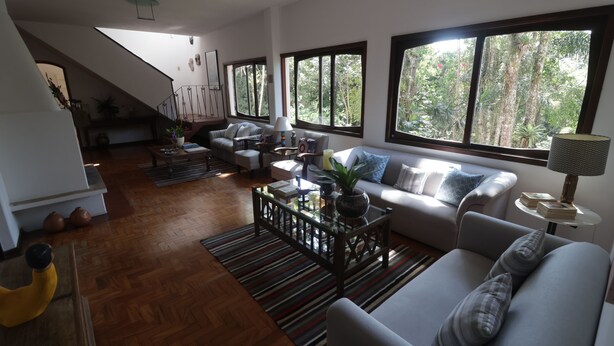 A spacious living room with a wooden floor, a sofa, a coffee table, and a staircase leading to another level. - Centro Paulus (São Paulo)