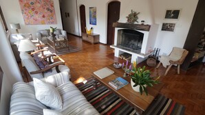 A cozy living room with a fireplace, striped sofas, and a coffee table with books and a plant. - Centro Paulus (São Paulo)