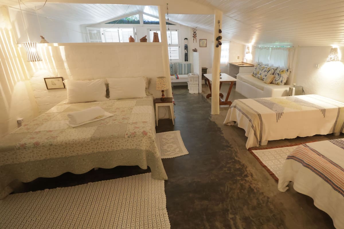 A cozy, well-lit room with two beds, a small table, and a chair.