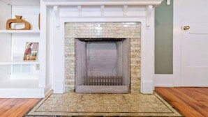 Une cheminée avec un foyer orné de carreaux, une cheminée blanche et un tableau encadré au-dessus.